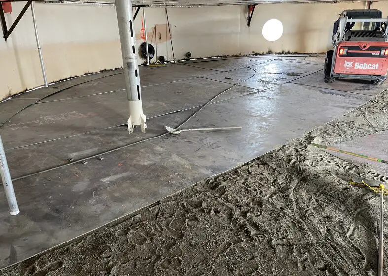 Concrete floor being poured and leveled inside a building.