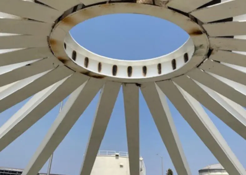 Circular skylight with radiating beams against a blue sky.