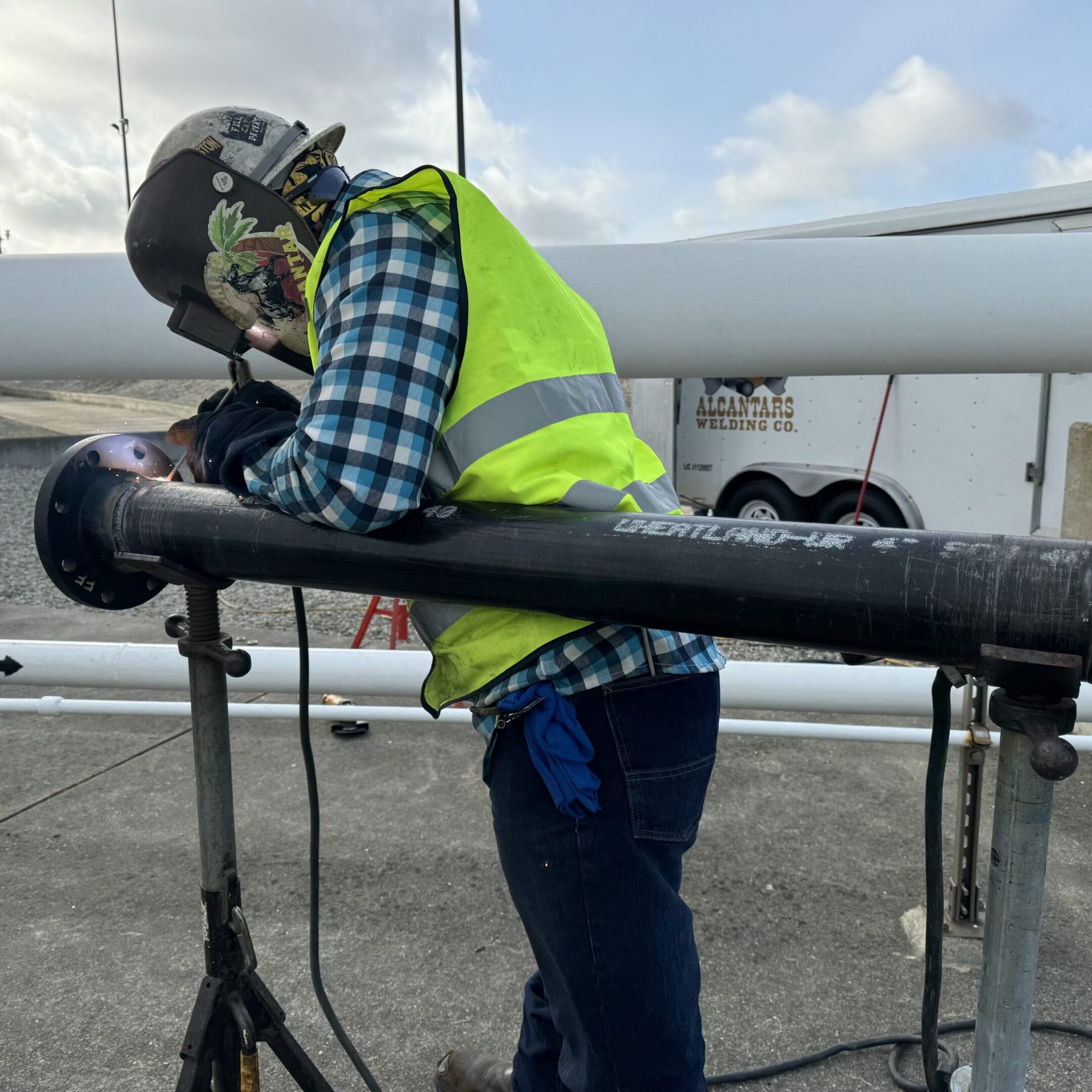 Worker in safety gear inspecting equipment outdoors.