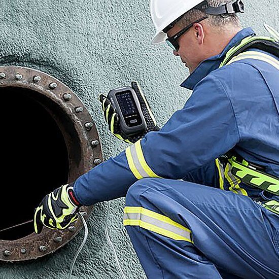 Technician inspecting inside a large industrial pipe with a camera.