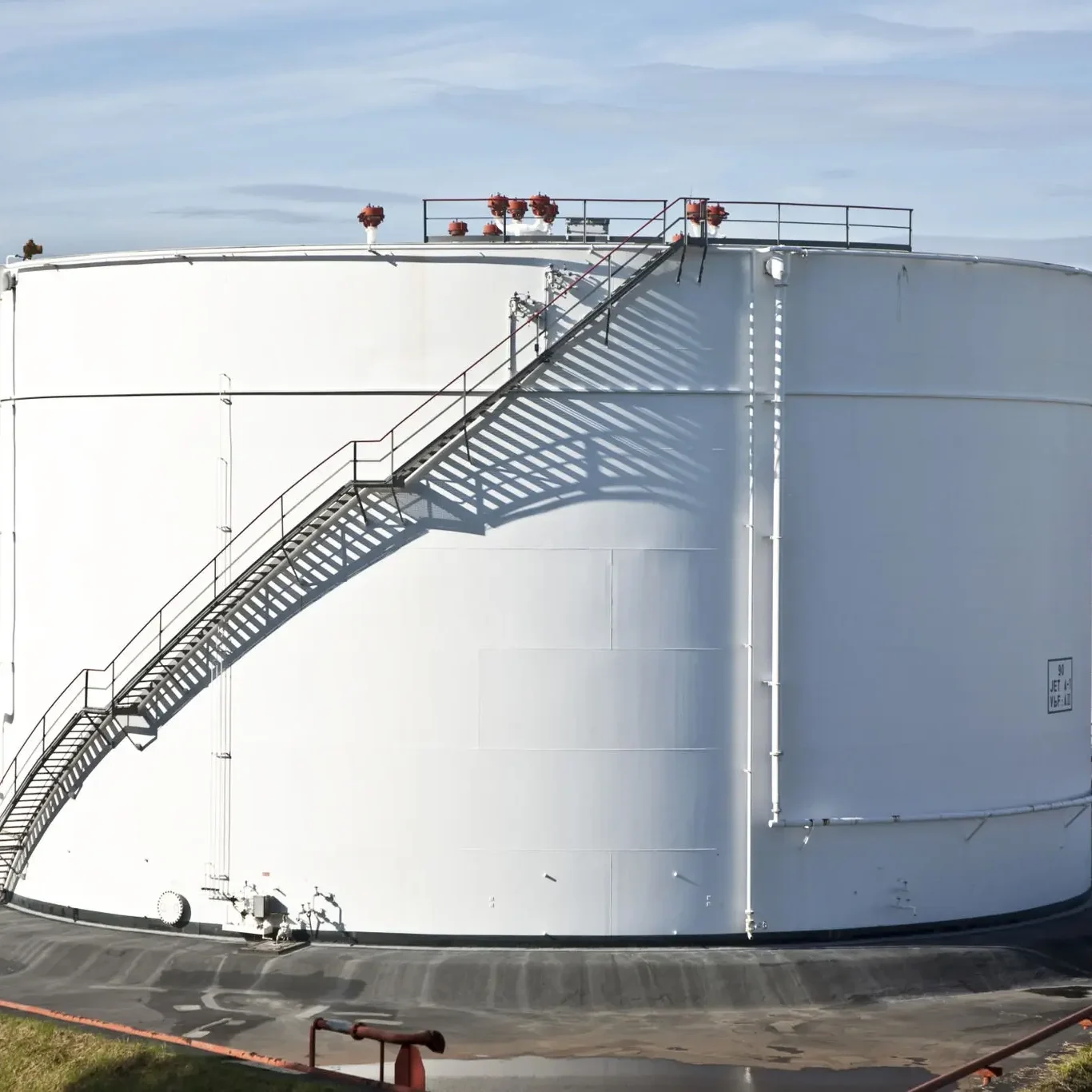 Large white industrial storage tank with external staircase.
